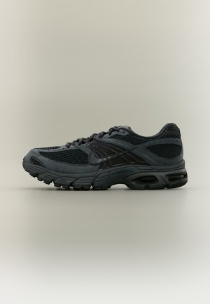 Scarpa sportiva nera e grigio scuro con tomaia in mesh e materiale sintetico, suola spessa imbottita e chiusura con lacci, vista dal lato su sfondo neutro.