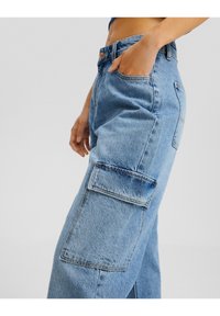 Light blue denim cargo pants with a loose fit, featuring a patch pocket on the thigh and faded texture throughout.