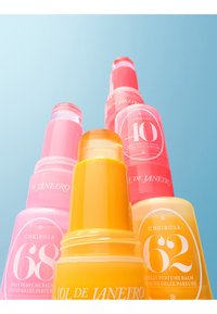 Cztery kolorowe sztyfty z perfumowanym balsamem Sol de Janeiro Cheirosa jelly w kolorach różowym, pomarańczowym i czerwonym na jasnoniebieskim tle.