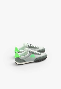 Hellgraue Sneakers mit grünen Akzenten, ausgestattet mit einem Totenkopfdesign, Materialien aus Wildleder und Netzstoff, weißen Schnürsenkeln und einer strukturierten schwarzen Gummisohle.