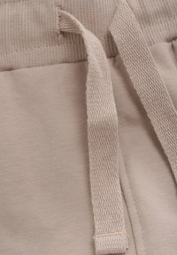 Ljusbeige joggers med en strukturerad midja och platt, vävd dragsko. Tyget är slätt med en subtil, enhetlig finish.