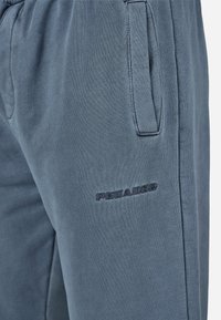 Μπλε βαμβακερό παντελόνι φόρμας με υφή, με πλαϊνές τσέπες και σκούρο κεντητό λογότυπο στον αριστερό μηρό.