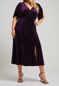 Lila, sammets midi-klänning med v-ringning, korta puffärmar och en sidöppning. Har texturerad tyg och en figursydd midja.