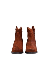 Botas de tobillo de ante marrón con una textura suave, lados curvados y lengüetas. Cuentan con una puntera redondeada y suelas negras sólidas.