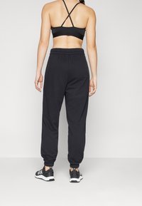 Svarta atletiska joggers med elastisk midja, uppvikta anklar och kombinerade med svarta sneakers. Enkelt designade med en åtsittande svart sport-bh.