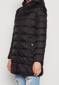 Svart puffjacka med huva, med horisontellt quiltat mönster, framsidan med dragkedja, sidofickor och en slät, glänsande yta.