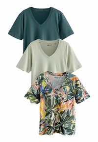 Tri v-neck majice: jedna tamnozelena, jedna svetlozelena i jedna s višebojnim tropskim uzorkom lišća na beloj pozadini.