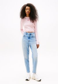 Light pink knitted crop sweater with cable pattern, paired with light blue high-waisted jeans and white sneakers.