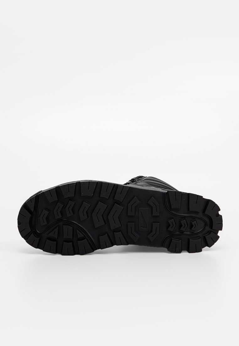 Semelle de botte de randonnée noire avec un motif de crampons robuste pour une traction, fabriquée en caoutchouc durable avec des rainures profondes et des formes angulaires.
