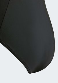Zwarte badstof met een gladde textuur, met een afgeronde rand en zichtbare stiksels. Geen patronen of accenten aanwezig.