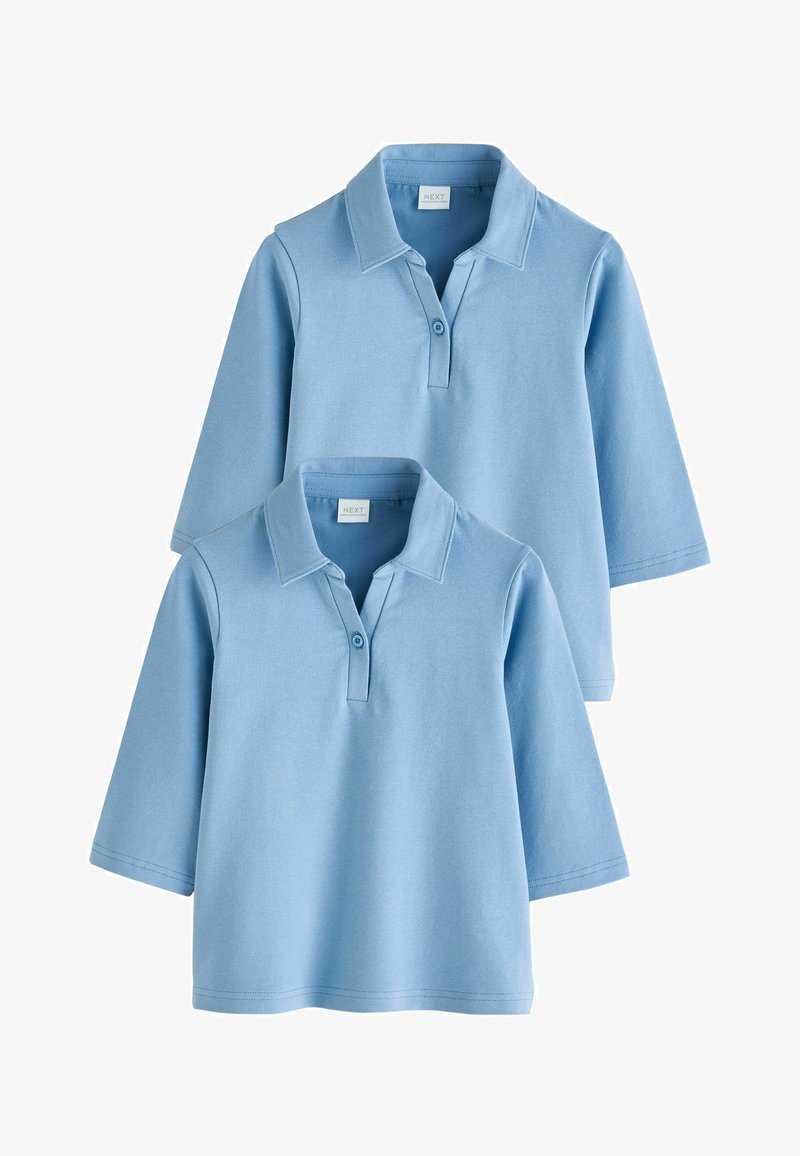 Hele sinised puuvillased poloteesärgid, lühikeste varrukatega, nööpidega kraega, millel on sile tekstuur ja lihtne disain. Kaks särki on üksteise peale virnastatud.