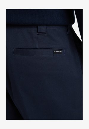 Pantalones azul marino fabricados con un material duradero y con un corte slim, que cuentan con un bolsillo trasero y una etiqueta del logo de Quiksilver en el borde del bolsillo.