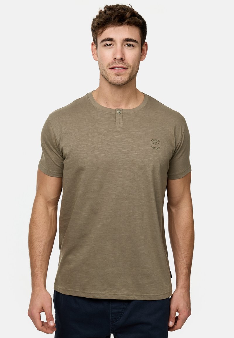 Olivgrünes, kurzärmeliges T-Shirt mit Rundhalsausschnitt, zwei Knöpfen und kleinem Logo auf der linken Brust. Weicher, texturierter Stoff.