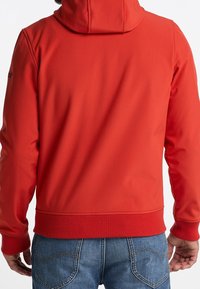 Sweat à capuche rouge avec une texture douce, doté d'une capuche réglable par cordon, de poignets et d'un ourlet côtelés. Détails comprenant des coutures le long des épaules et des coutures.