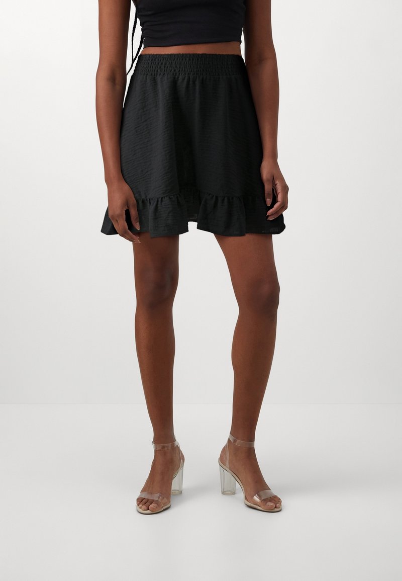 Černá texturovaná mini sukně s volánovým lemem. Elastický pas pro pohodlné nošení. V kombinaci s transparentními sandály na blokovém podpatku.