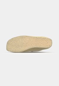 Beige rubber shoe sole with textured grip pattern, featuring a curved shape and slight elevation at the heel.