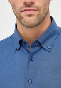 Camicia button-up blu a motivo a spina di pesce con colletto sartoriale e bottoni a contrasto, che mette in risalto un tessuto testurizzato.