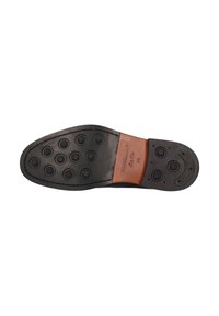 Czarna gumowa podeszwa z okrągłymi wzorami grip, skórzany akcent na pięcie oraz wytłaczane detale. Płaski, solidny design zapewniający trwałość.