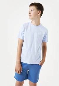 T-shirt en coton bleu clair avec un col rond et des manches courtes, associé à un short bleu arborant un logo discret sur l'ourlet.