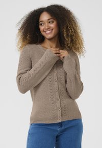 Brown ribbed cardigan with a V-neck, pearl buttons, and floral stitch accents on sleeves. Soft texture and relaxed fit.