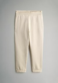 Cremefarvede sweatpants lavet af blødt stof, med elastisk talje og smalle manchetter ved anklerne. Glat overflade hele vejen igennem.