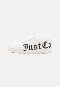 White sneakers made of synthetic material, featuring black cursive text "Just Cal" on the side, with a flat rubber sole and textured detailing.