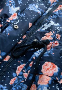 Navy blue rain jacket with floral and star patterns; features a zipper, snap fastening, and adjustable drawcord at the hem.