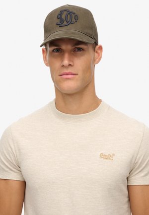 Oliven grøn baseball cap med broderet logo, parret med en beige strikket t-shirt med diskrete striber og et lille broderet brandnavn.