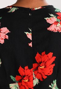Vestido de tela negra con un estampado floral que presenta grandes flores rojas y rosas, un escote redondo y un cierre de cremallera en la parte posterior.