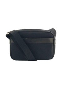 Bolso cruzado de tela negra con cierre de cremallera, correa ajustable y un acento de cuero suave. Forma rectangular con un sutil detalle de logo.