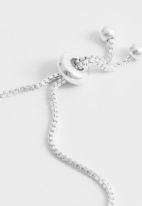 Silberne Metallhalskette mit einer glatten, runden Perle, strukturierten Kettengliedern und Kugelakzenten. Das Design ist minimalistisch mit einer eleganten Oberfläche.