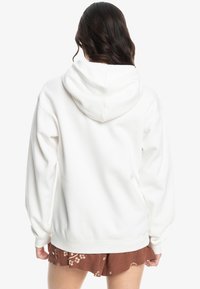 Witte oversized hoodie met een trekkoordcapuchon, geribbelde boorden en zoom. Zachte stof met een gladde textuur, die een ontspannen pasvorm vertoont.