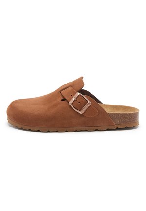 Sabots en daim marron avec une seule sangle réglable avec boucle en métal, semelle intérieure texturée et semelle intermédiaire en liège avec un motif.