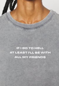 Szara bluza z prążkowanym dekoltem, z białym nadrukiem o treści "JEŚLI TRAFIM DO PIEKŁA, TO PRZYNAJMNIEJ BĘDĘ Z WSZYSTKIMI MOIMI PRZYJACIÓŁMI."