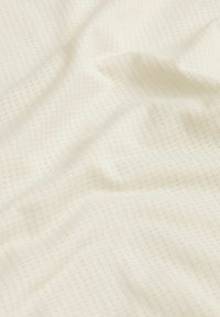 Tissu crème texturé avec un motif de grille subtil, offrant une surface lisse et un drapé doux. Idéal pour diverses applications textiles.