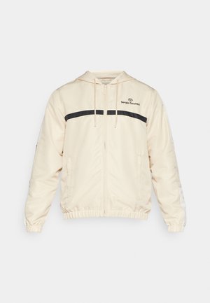 Light beige jacket featuring a zip front, hood, black horizontal stripe, and ribbed cuffs. Logo printed on the upper left chest.