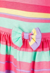 Randig klänning med rosa, grön och gul färg, med en rynkad fåll och en rosettdekoration i lila och gul tyg.