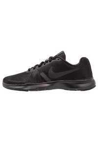 Black athletic shoes with a mesh upper, featuring textured stripes, a rounded toe, and a cushioned sole. Nike logo displayed on the side.