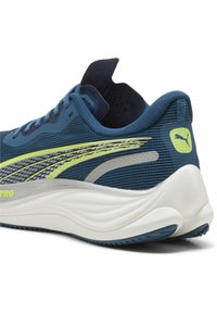 Scarpa da corsa blu con tomaia in rete, accenti gialli e argentati, suola bianca curva e collare imbottito per il comfort.