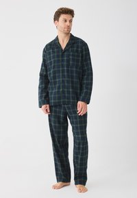 Férfi flanel pizsama szett sötétzöld és tengerészkék kockás mintával, gombos felsővel, mellzsebekkel és hozzá illő, laza fit pántos nadrággal.