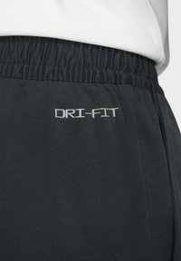 Svarta DRI-FIT träningsbyxor med elastisk midja, med en mjuk textur och subtil lyster. Logotyp i ljusgrått på sidan.