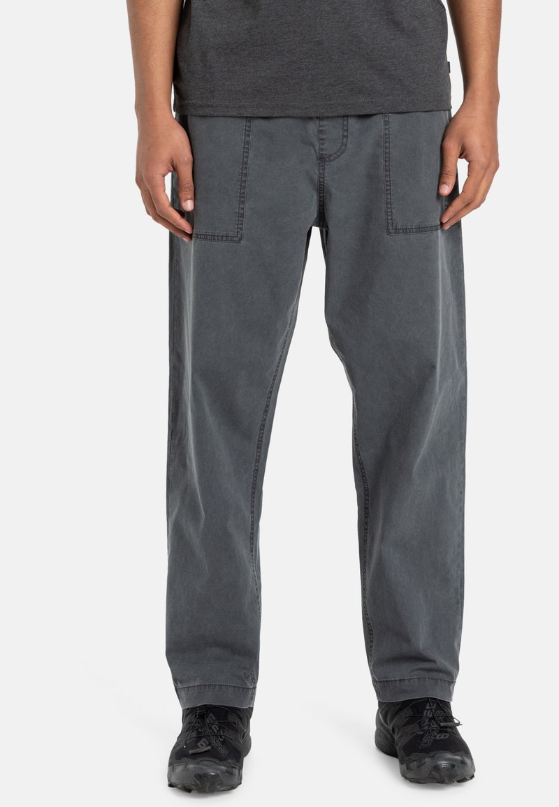 Pantalons cargo en coton gris avec une coupe décontractée, dotés de deux poches avant et de détails cousus. Portés avec des chaussures noires.