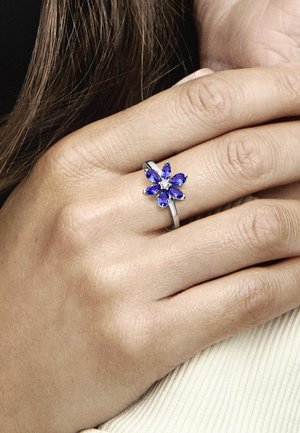 Anello floreale con gemme di quarzo viola a forma di marquise e una gemma rotonda centrale, montato su una fascia in argento lucidato.