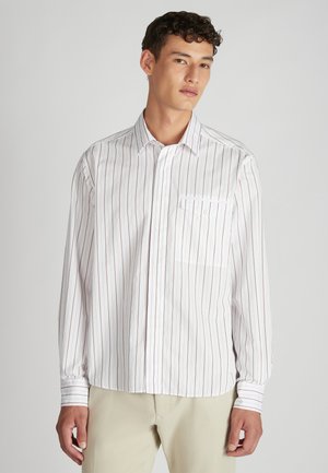 Wit overhemd met lange mouwen en dunne verticale rode strepen, met button-down kraag en een borstzak, gecombineerd met beige broek. Gladde textuur.