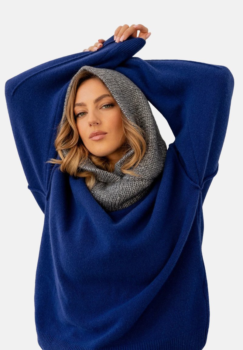 Niebieski oversize sweter z dekoltem typu cowl i szarym dzianinowym kapturem. Miękka faktura, opuszczone ramiona i szerokie rękawy.