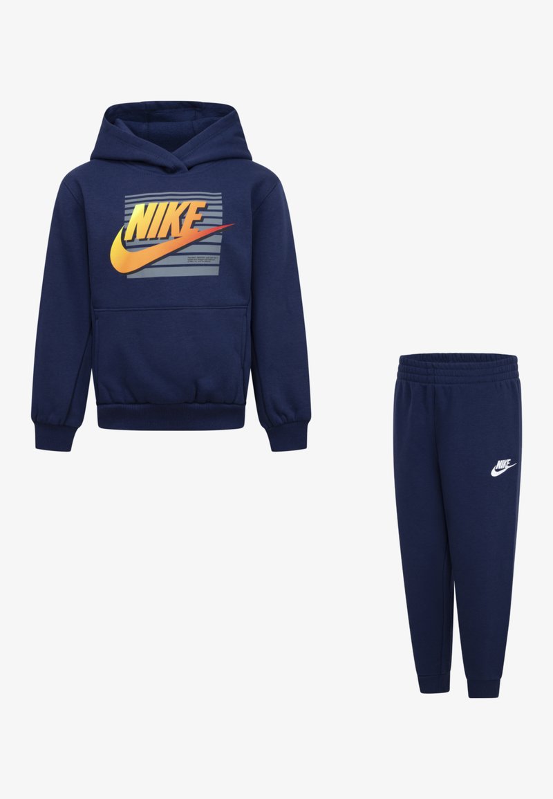 Dunkelblaue Hoodie- und Jogginghosenkombination aus weichem Stoff; mit einer vorderen Kängurutasche und prominentem Nike-Logo in Gelb und Orange auf dem Hoodie.