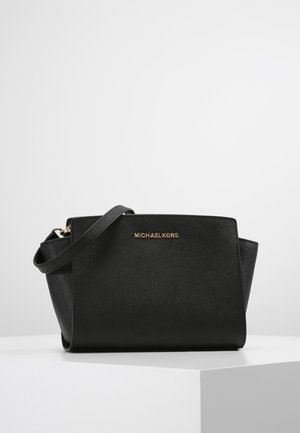 Black leather handbag with a structured shape, featuring a gold logo, a detachable strap, and a smooth texture.