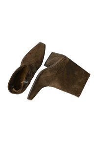 Botines de ante marrón con punteras afiladas y tacones cortos de madera apilada, uno visto de lado y el otro desde arriba con la cremallera visible.