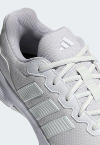 Biele športové topánky s textúrovaným zvrškom, tromi pruhovanými akcentmi, okrúhlymi šnúrkami a polstrovaným golierom.