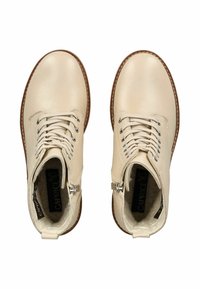 Bottes chevilles en cuir beige avec une finition texturée, bout rond, devant à lacets et fermeture éclair intérieure. Semelle en caoutchouc marron avec des accents de couture.